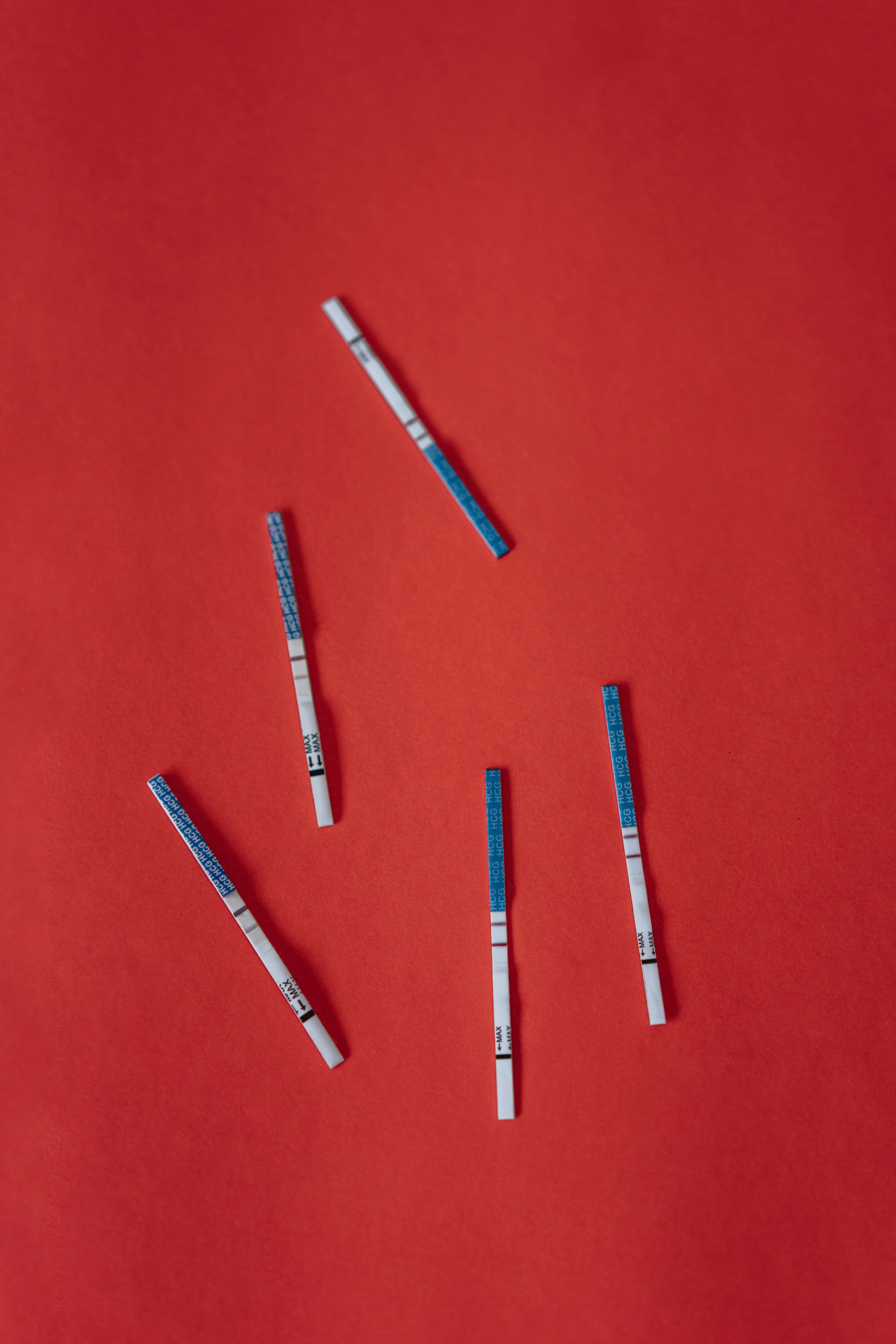 Pregnancy test strips scattered on a red background